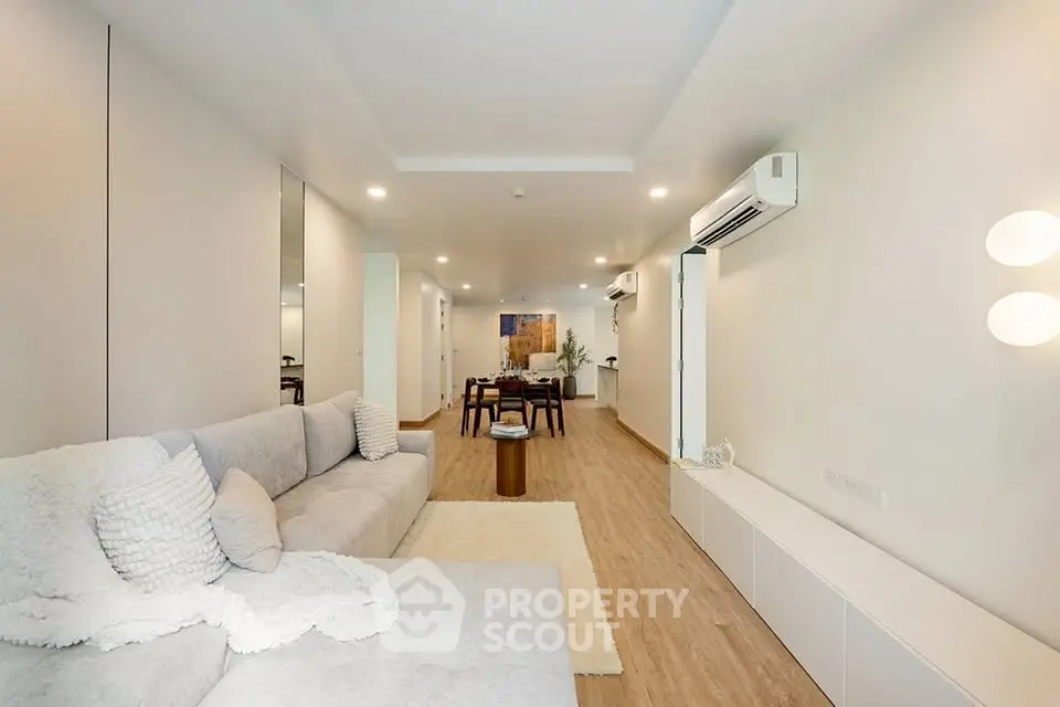 Spacious modern living room with cozy sofa and elegant dining area, featuring stylish lighting and air conditioning.