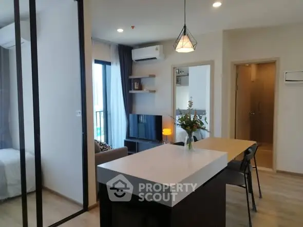 Modern open-plan living room with dining area and bedroom view in a stylish apartment.