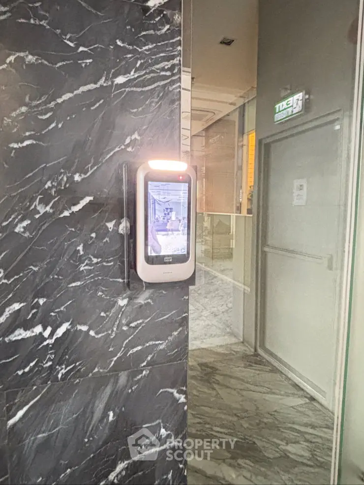 Modern building entrance with sleek marble walls and advanced security system.