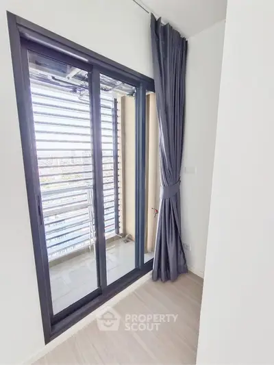 Modern apartment with sliding glass doors leading to a balcony, featuring sleek curtains and a bright interior.