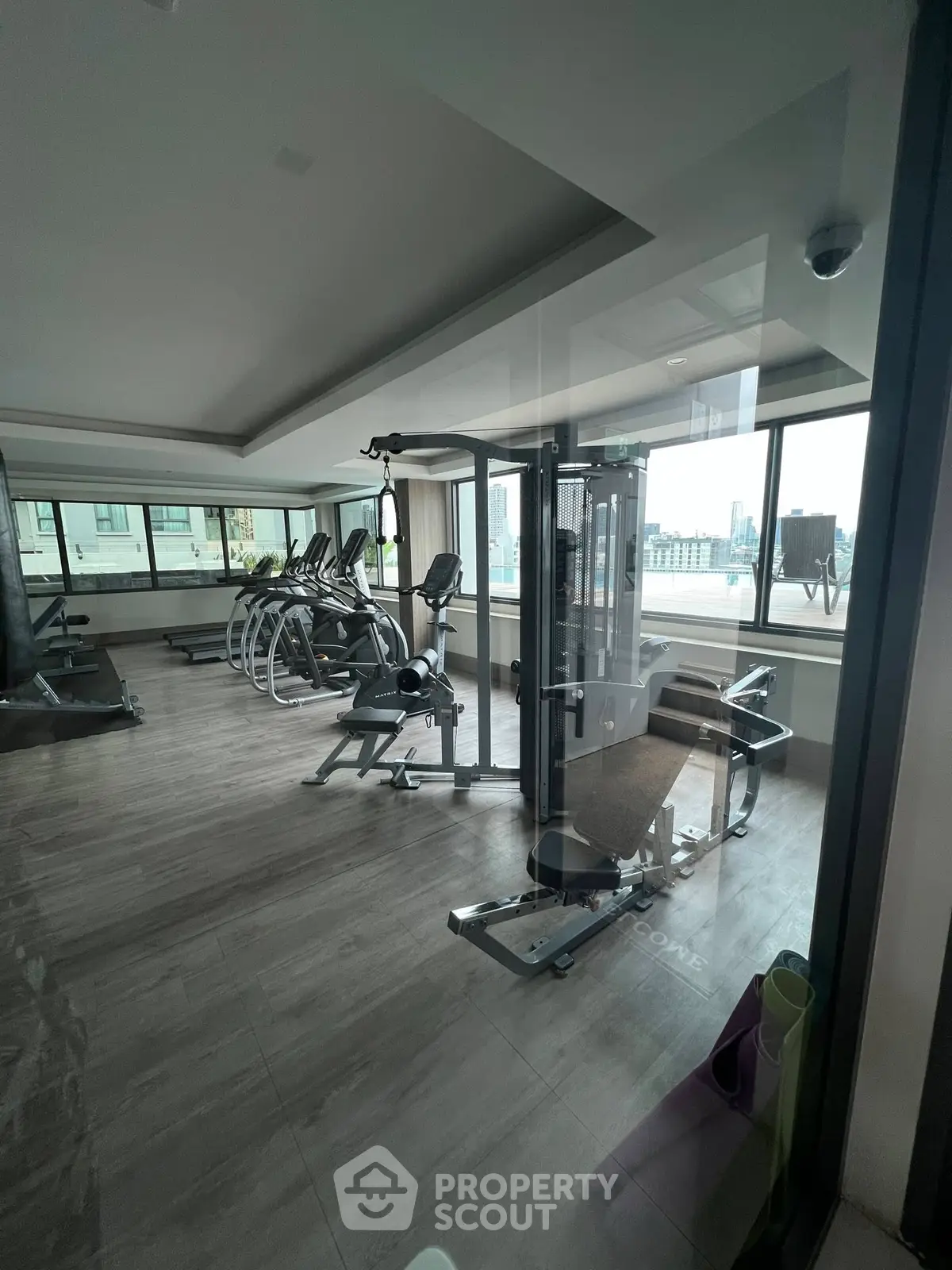 Spacious gym with modern equipment and city view in luxury building.