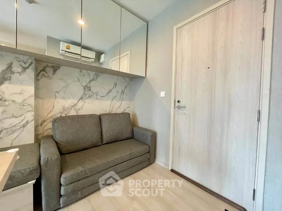 Modern living room with stylish sofa and marble accent wall in a cozy apartment.