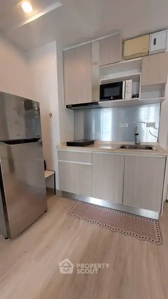 Modern compact kitchen with sleek cabinetry and stainless steel appliances in a stylish apartment.