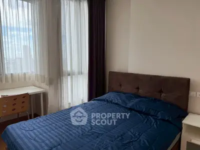 Cozy bedroom with blue bedding and natural light from large windows