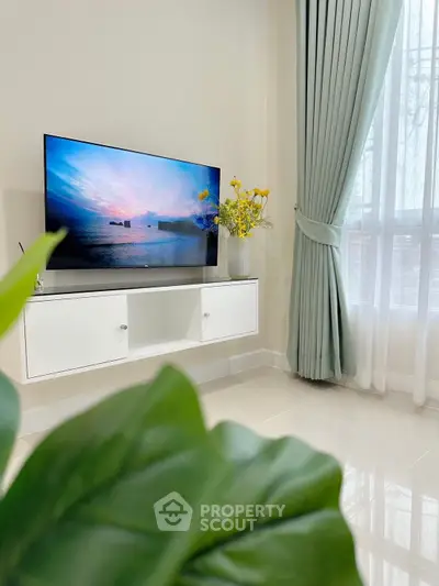 Modern living room with sleek TV setup and elegant curtains, perfect for cozy evenings.