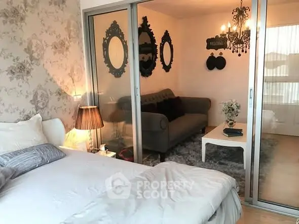 Chic bedroom with sliding glass doors to cozy living area, elegant decor and soft lighting.