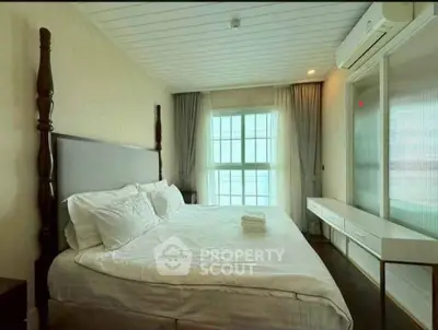 Spacious bedroom with elegant decor and large window offering natural light.