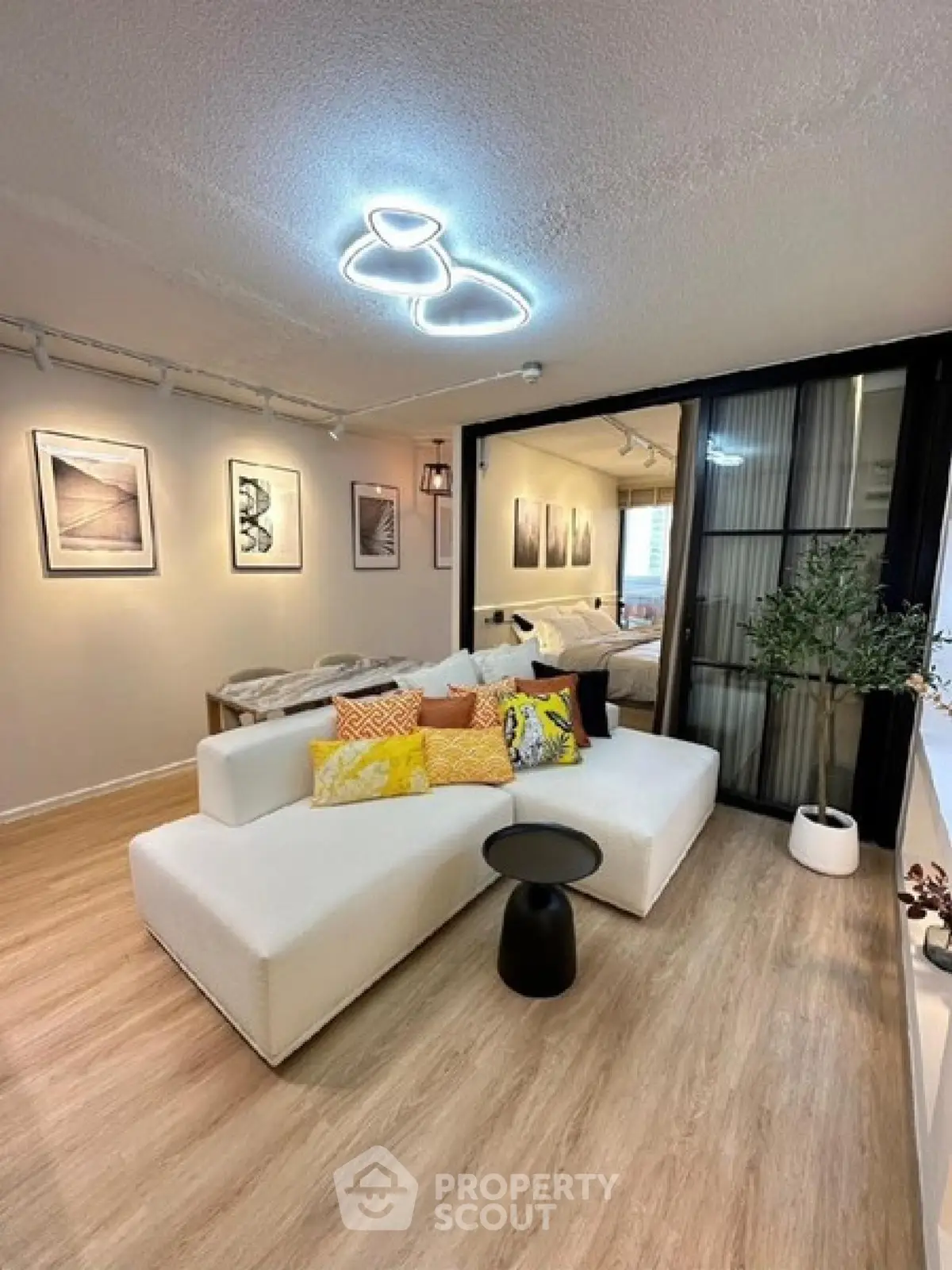 Modern living room with stylish lighting and cozy seating area, featuring elegant decor and wooden flooring.