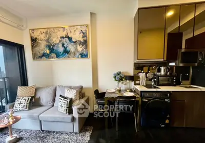 Modern living room with stylish decor, compact kitchen, and balcony access in a cozy apartment.