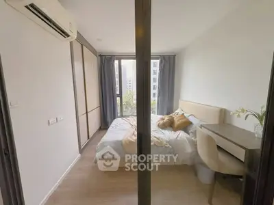 Modern bedroom with large window, stylish decor, and built-in wardrobe in a cozy apartment.