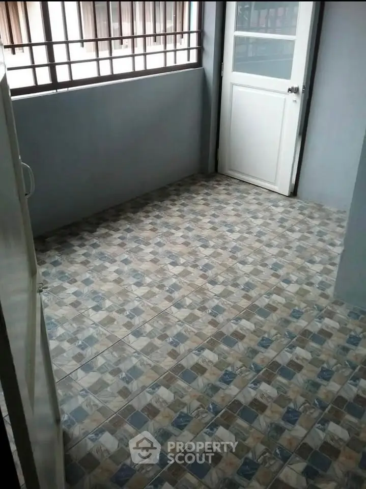 Spacious tiled balcony with secure railing and white door access.