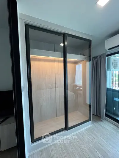 Modern bedroom with sleek glass wardrobe and natural light