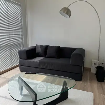 Modern living room with sleek black sofa and stylish glass coffee table.