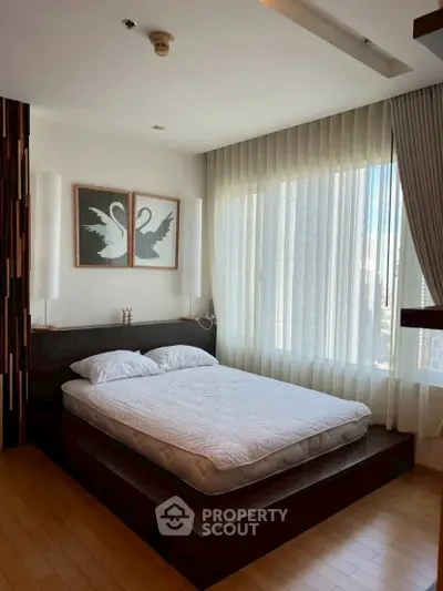 Modern bedroom with large windows and elegant decor in a high-rise apartment.