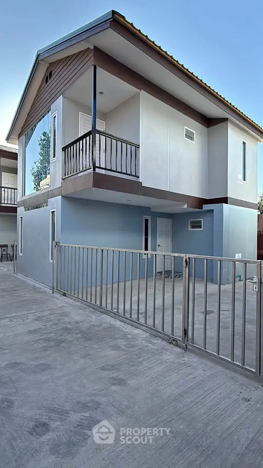 Modern two-story house with balcony and gated driveway