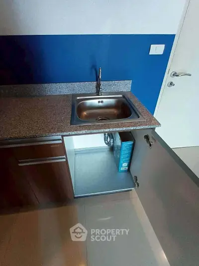 Modern kitchen with sleek granite countertop and stainless steel sink, featuring a minimalist design and elegant cabinetry.
