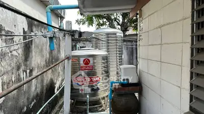 Outdoor area with stainless steel water tanks and plumbing in a residential setting.
