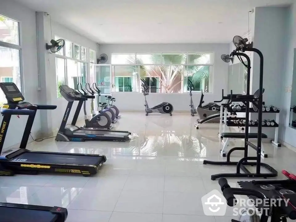 Spacious and well-equipped gym with modern fitness machines and bright natural lighting.