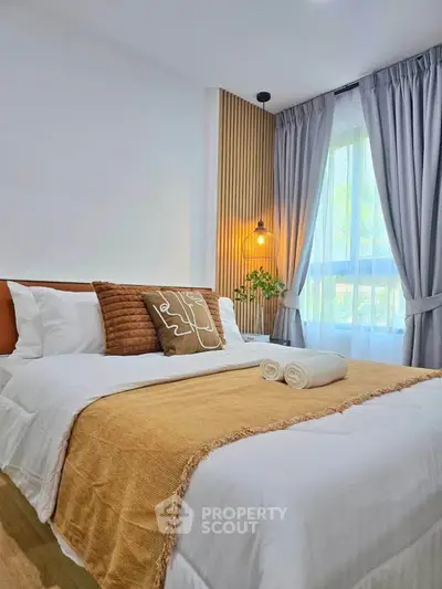 Cozy bedroom with elegant decor and natural light, featuring a stylish bed and soft curtains.