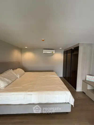 Spacious bedroom with modern design and large bed, featuring sleek built-in wardrobe and air conditioning.