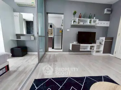 Modern living room with sleek design, featuring a wall-mounted TV, stylish shelving, and a glimpse into a contemporary kitchen.