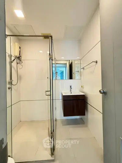 Modern bathroom with glass shower enclosure and sleek vanity in a contemporary apartment.