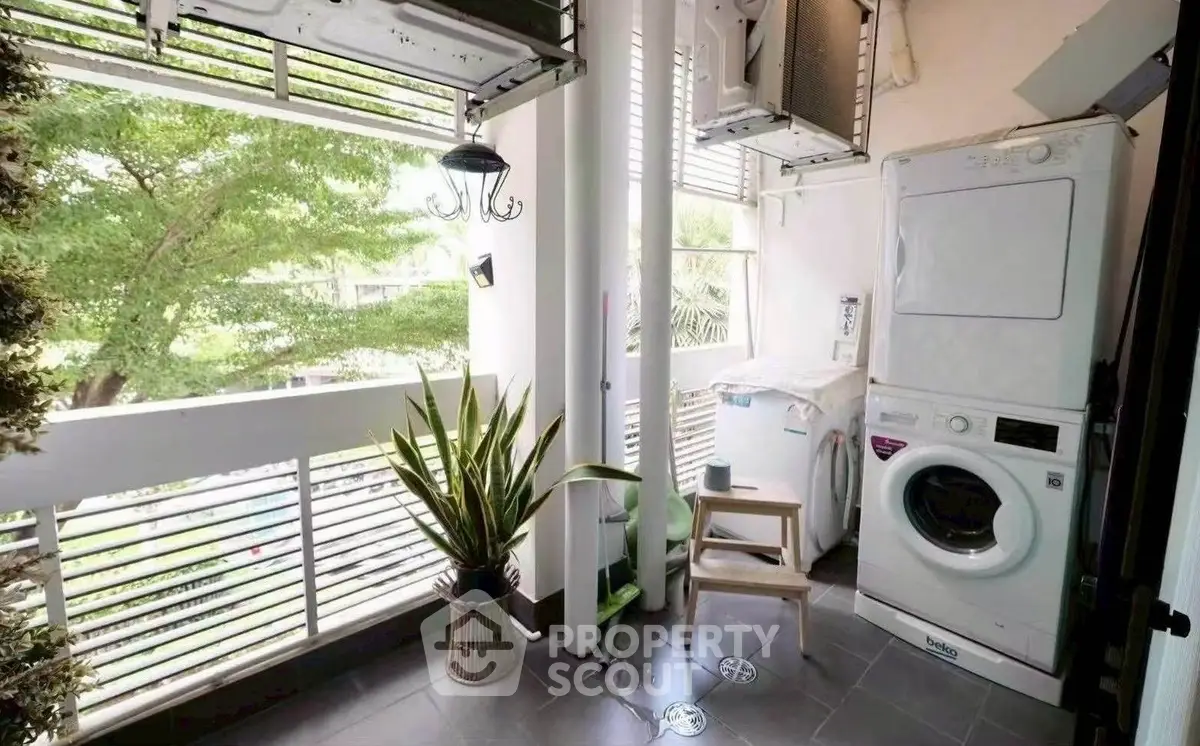 Charming balcony with laundry area and lush greenery view.