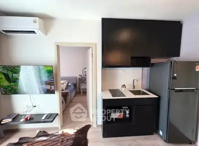 Modern kitchen with sleek black cabinets and integrated appliances in a stylish apartment.