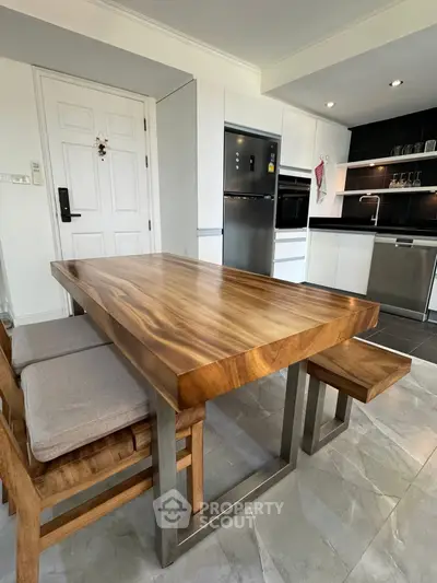 Modern kitchen with sleek appliances and stylish wooden dining table.