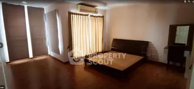 Spacious bedroom with wooden flooring and large windows for natural light.