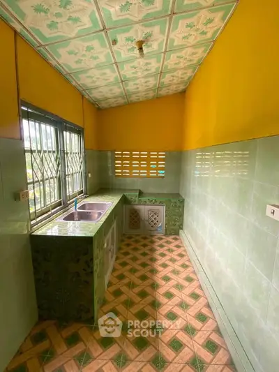 Charming kitchen with vibrant green tiles and ample natural light, perfect for culinary creativity.