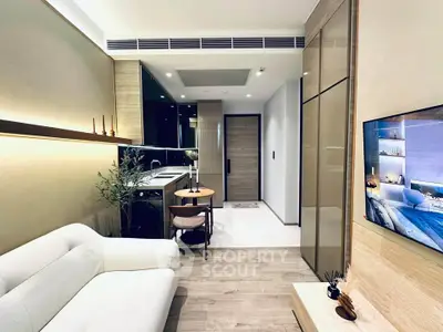 Modern living room with open kitchen, sleek design, and cozy ambiance in a stylish apartment.