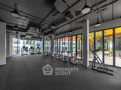 Spacious modern gym with large windows and state-of-the-art equipment in luxury residential building.