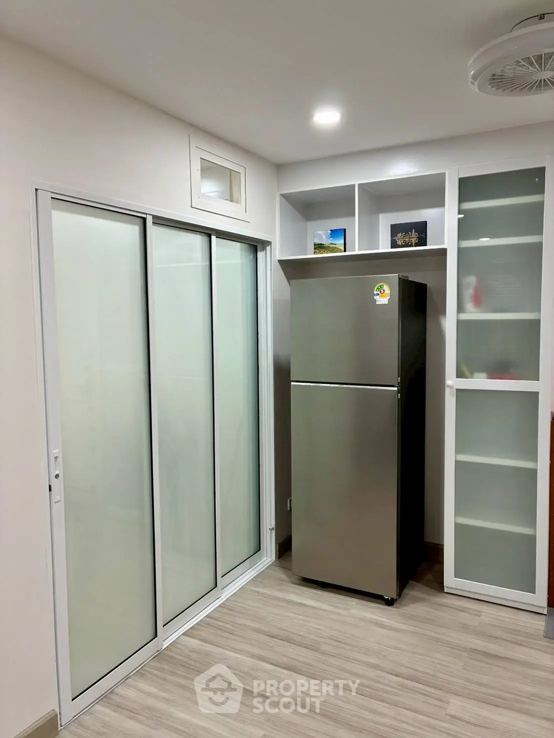 Modern kitchen with sleek fridge and sliding glass doors in a stylish apartment.