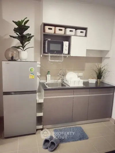 Modern kitchen with sleek cabinets, stainless steel fridge, and microwave, perfect for urban living.