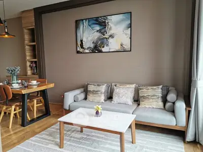 Stylish living room with modern decor and dining area, featuring elegant artwork and cozy seating.