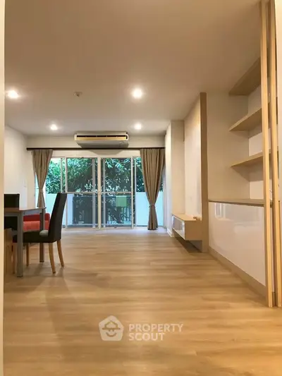Spacious living room with modern decor and large windows offering a serene garden view.