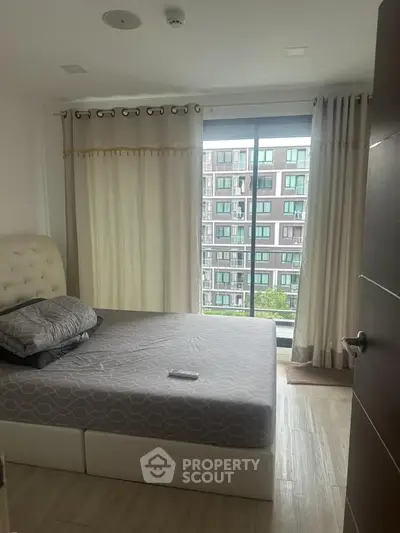 Modern bedroom with large window and city view in urban apartment