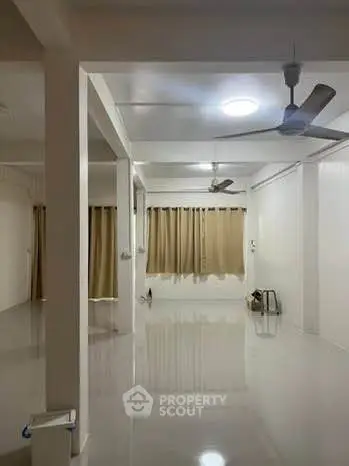 Spacious open-plan living area with ceiling fans and large windows.