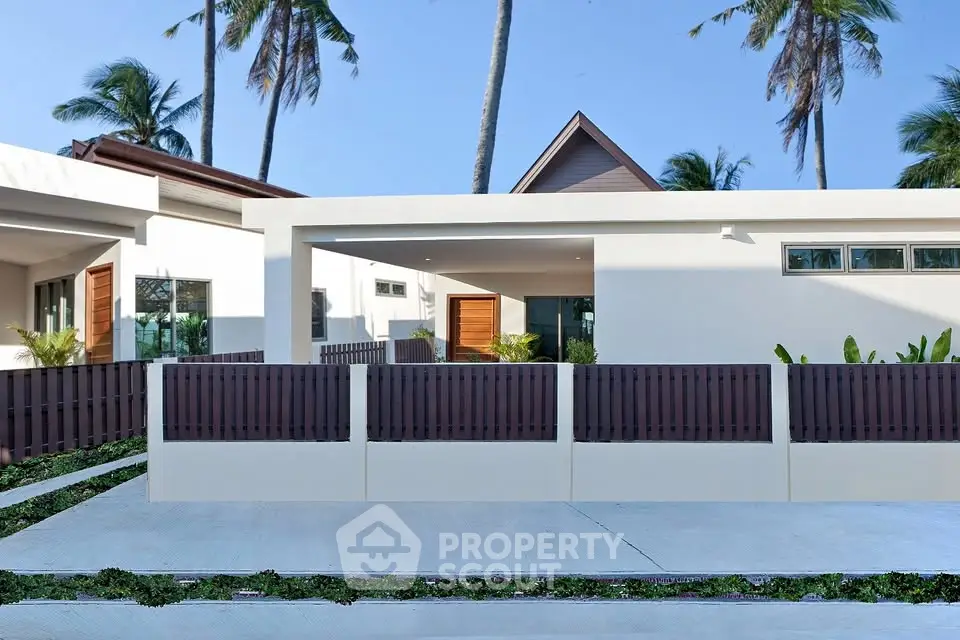Modern tropical villa exterior with sleek design and lush palm trees.