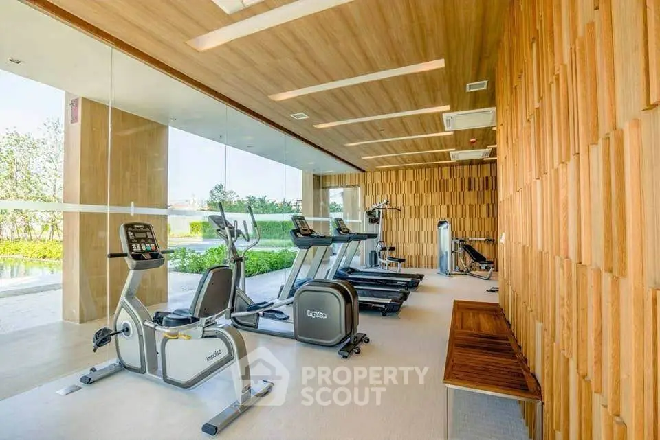 Luxurious gym with modern equipment and wooden accents in a serene setting.
