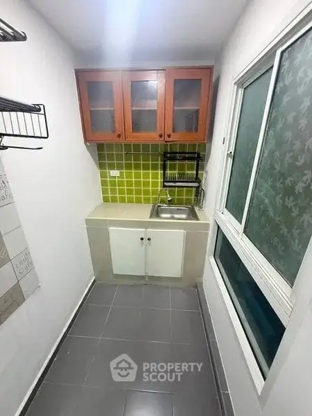 Compact kitchen with green tile backsplash and wooden cabinets