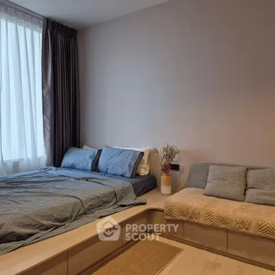 Modern bedroom with cozy bed and stylish seating area, featuring elegant decor and natural light.