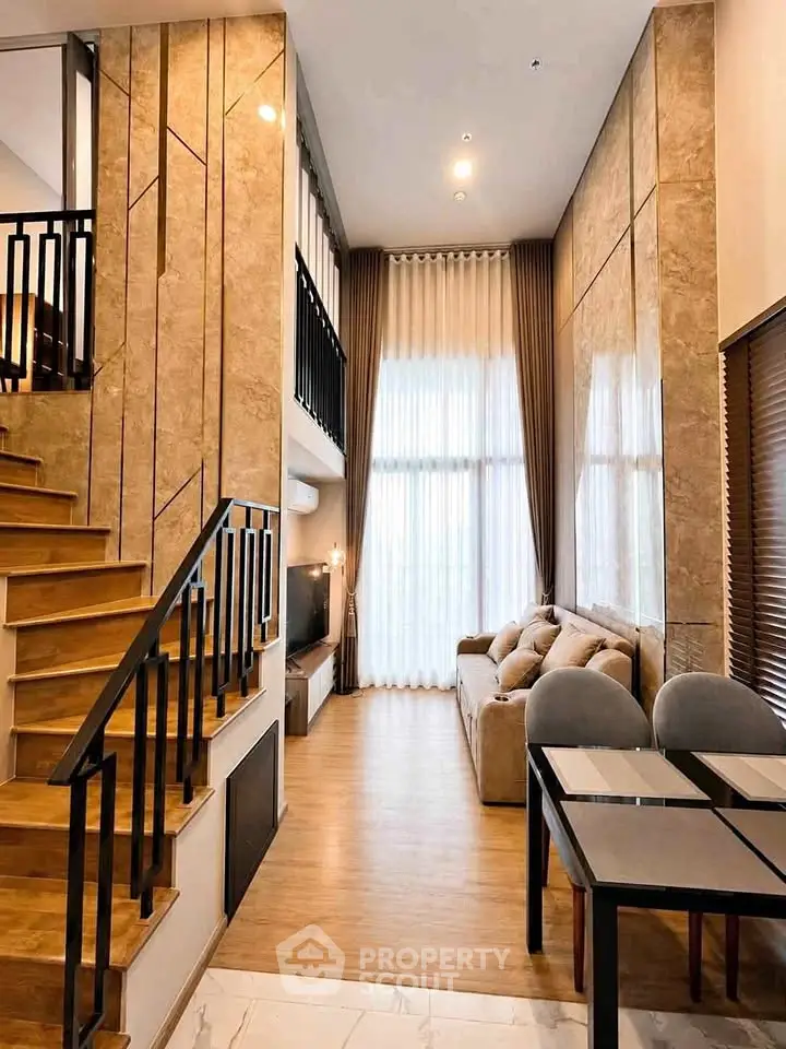 Luxurious modern living room with high ceilings and elegant staircase in a stylish apartment.