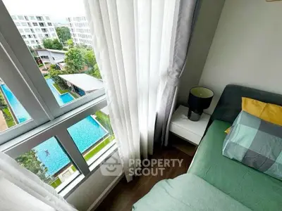 Cozy bedroom with a stunning pool view, featuring modern decor and ample natural light through large windows.