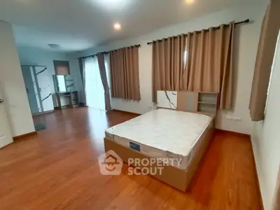 Spacious bedroom with wooden flooring and natural light