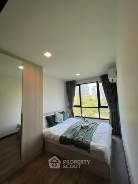 Modern bedroom with large window and stylish decor in a high-rise apartment.