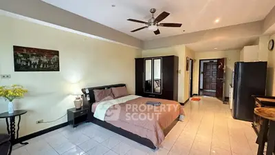 Spacious bedroom with modern furnishings and ceiling fan in a well-lit apartment.
