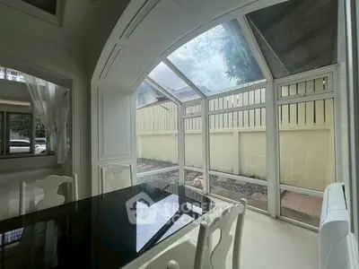 Elegant dining area with glass walls offering a serene garden view, perfect for natural light lovers.