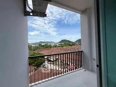 Stunning balcony view overlooking rooftops and lush hills, perfect for serene living.